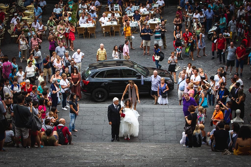 crowd surrounding a bride and her father climbing the stairs of Amalfi cathedral in amalfi coast