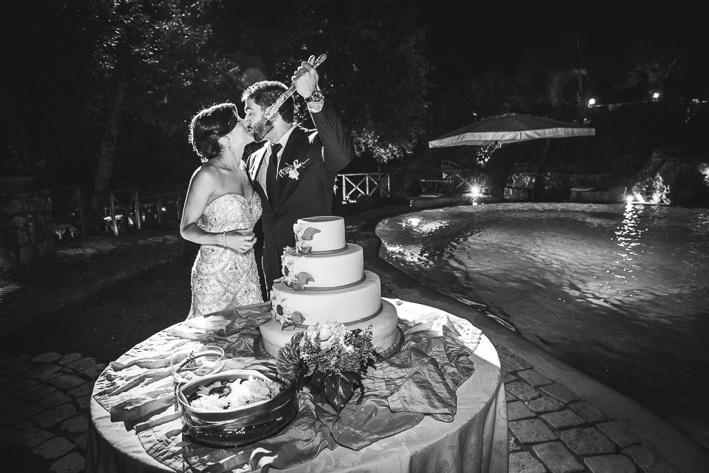 a groom jokingly points a knife at his wife at wedding cake