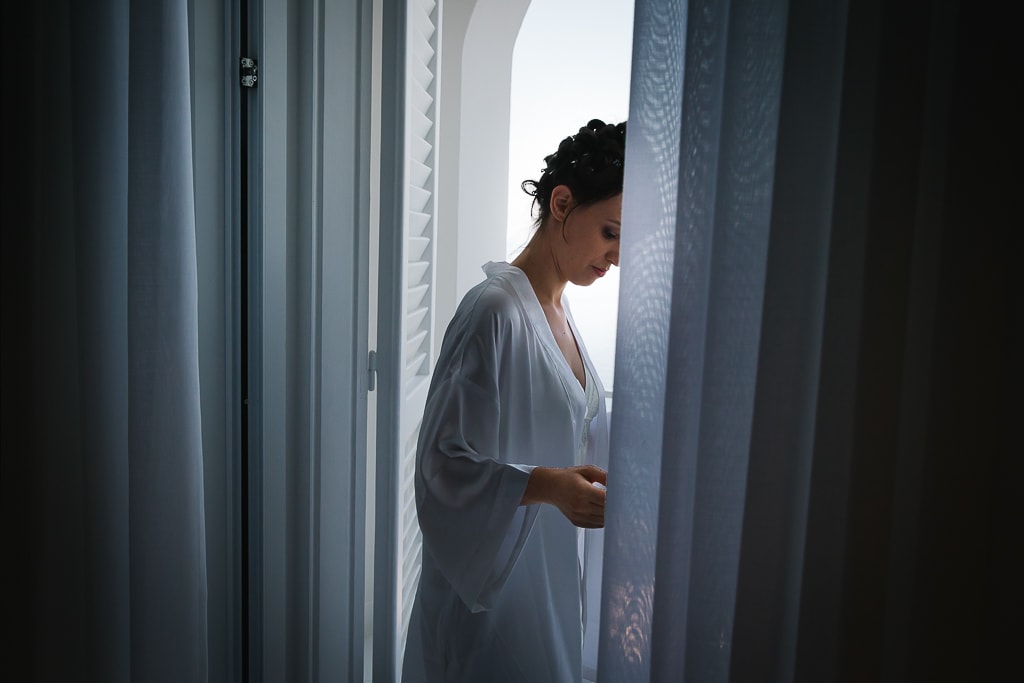 bride getting ready in her hotel room in front of the window