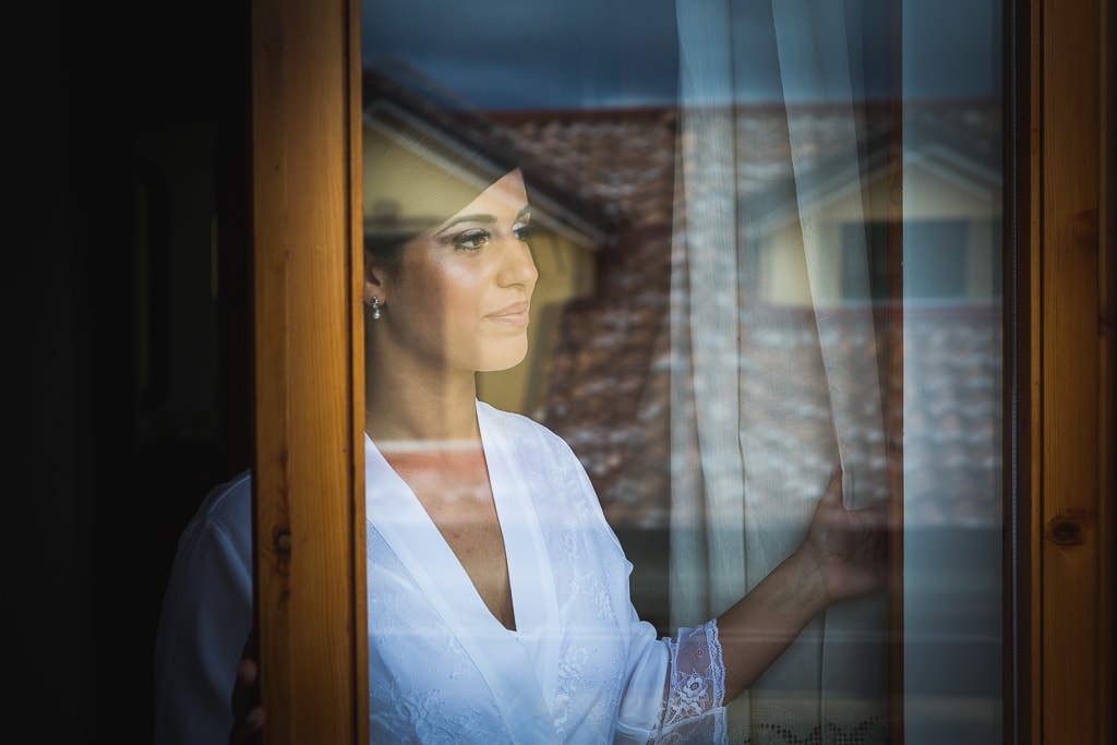 a bride looking outside through the window glass