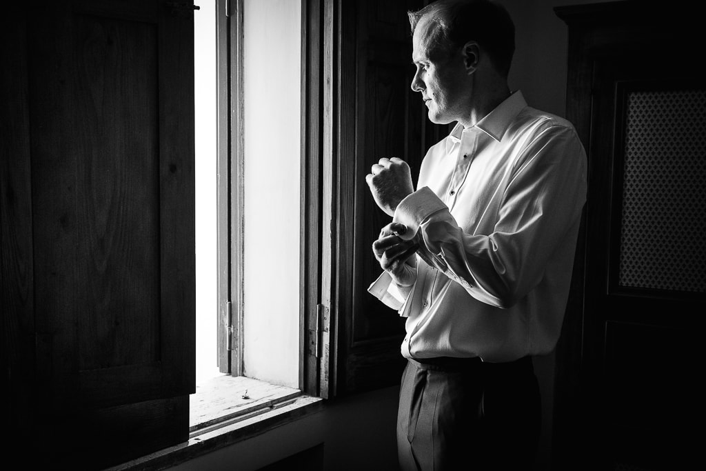 groom gets ready while looking outside the window