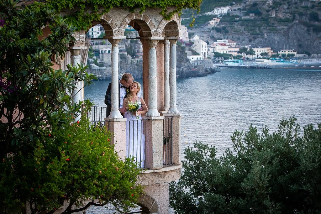 wedding couple on the balcony of villa scarpariello in amalfi coast and the town of minori in the background