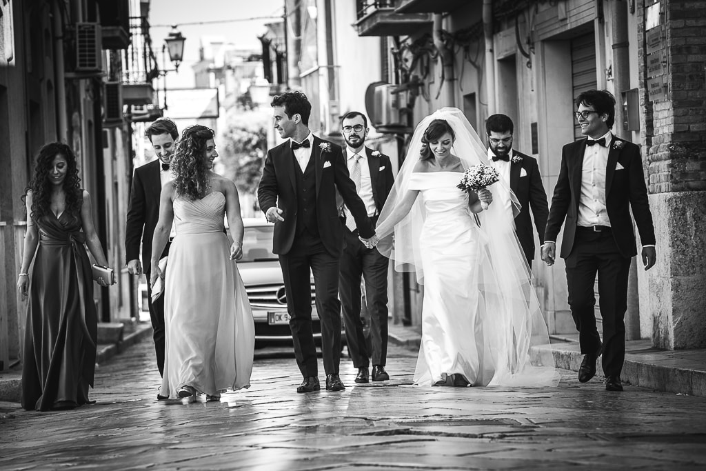 wedding couple and friends walking in the streets of a town in apulia
