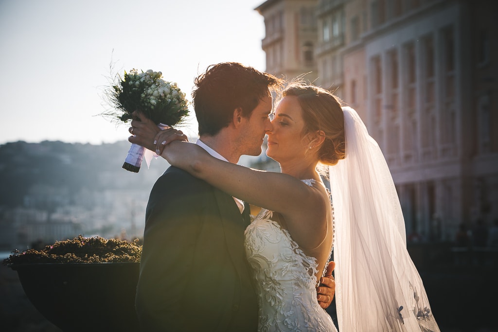 wedding couple in warm light at sunset and buildings in the background