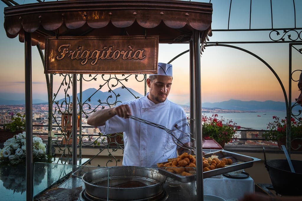 a chef prepares the fry at a wedding reception in naples and the vesuvio in the background
