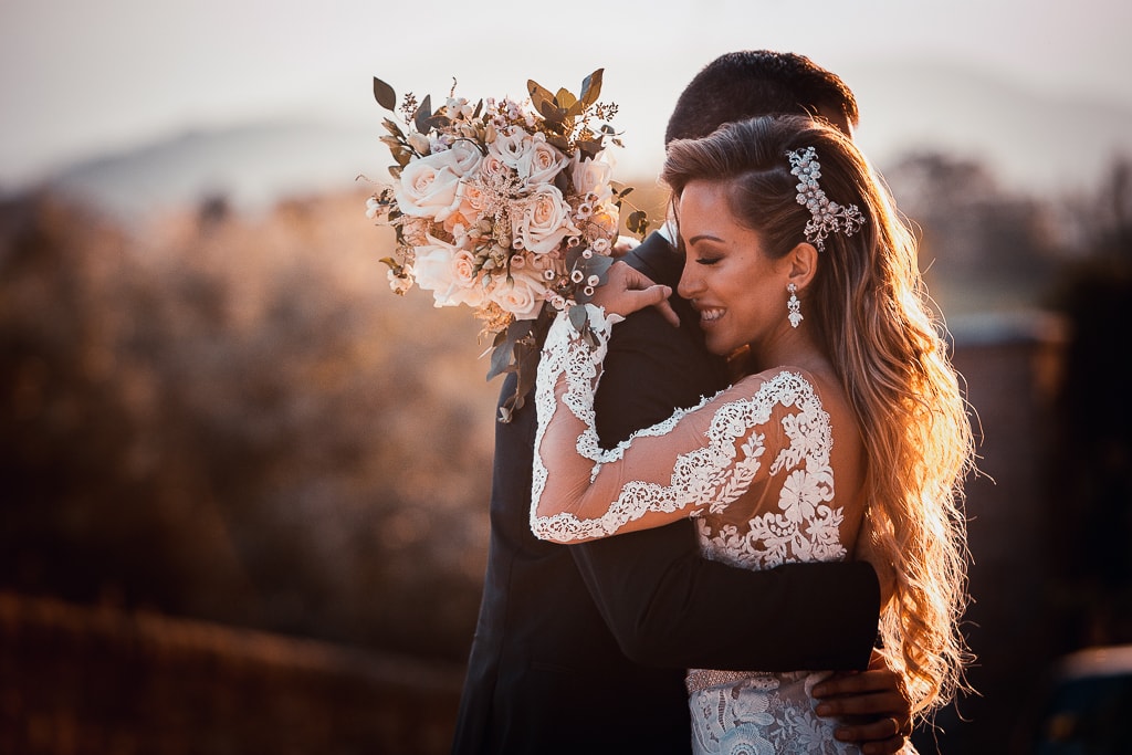 the hug of a wedding couple in a warm light at sunset