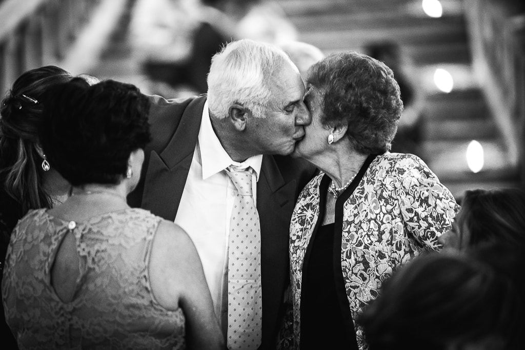 an elderly couple kissing at a wedding