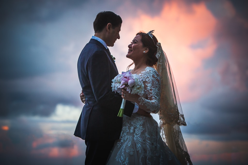 wedding couple at sunset with pink clouds in the background