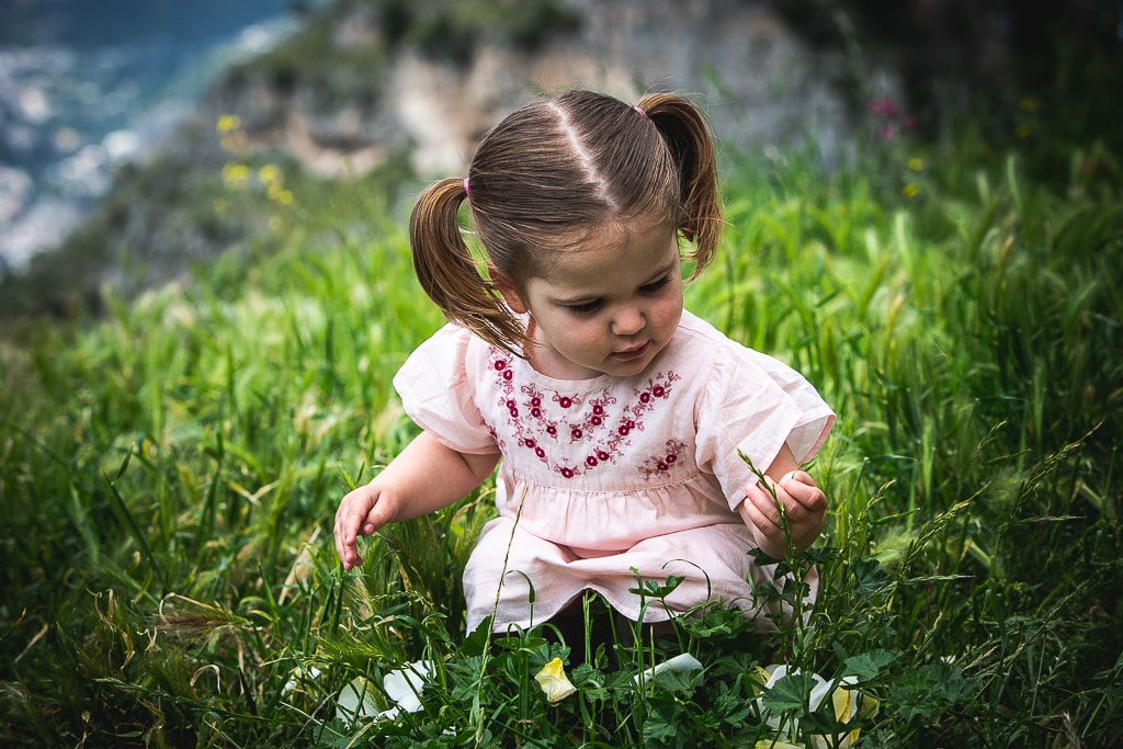 a little girl collects flowers in a garden at a wedding