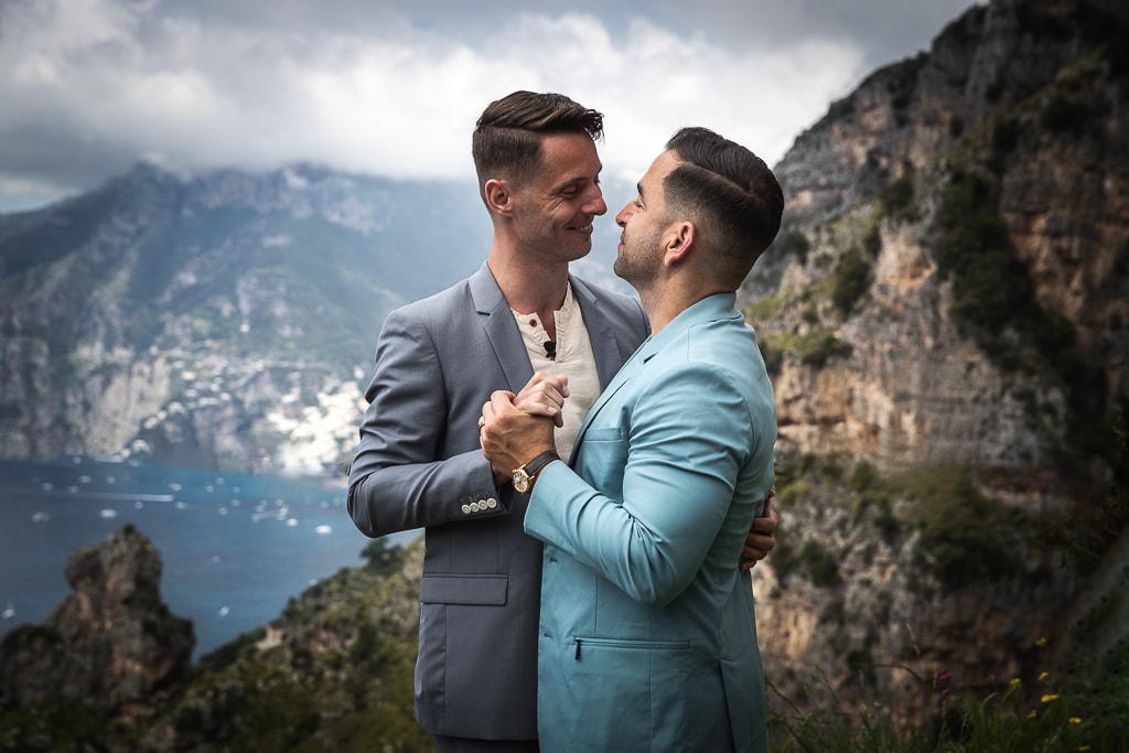 gay couple dancing on a terrace overlooking amalfi coast cliffs