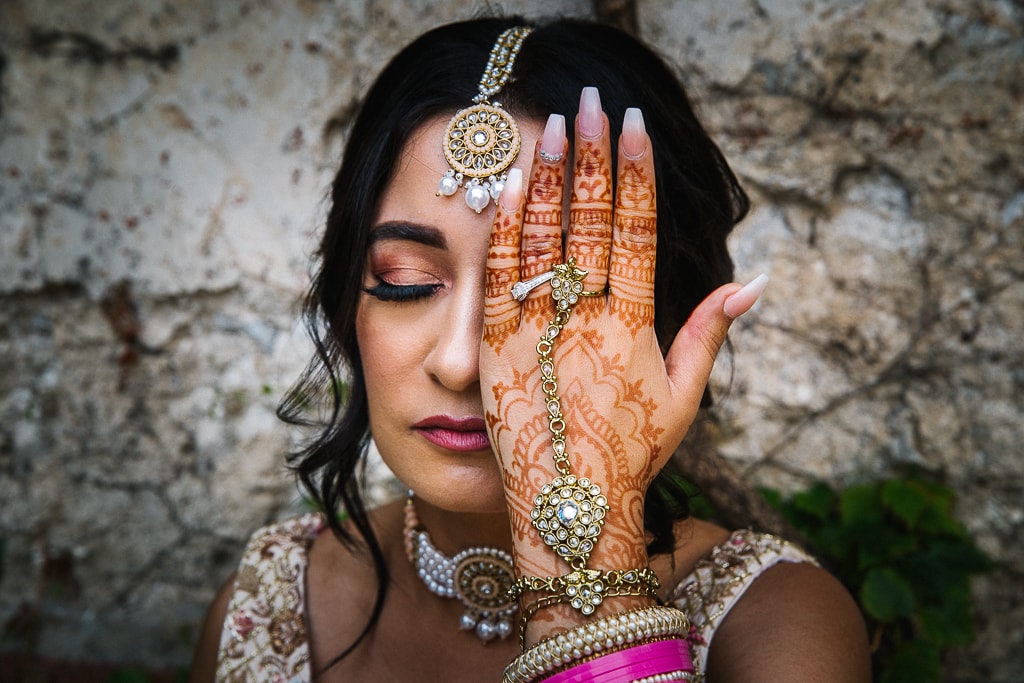 hindu bride covers her eye with her hand showing her henna