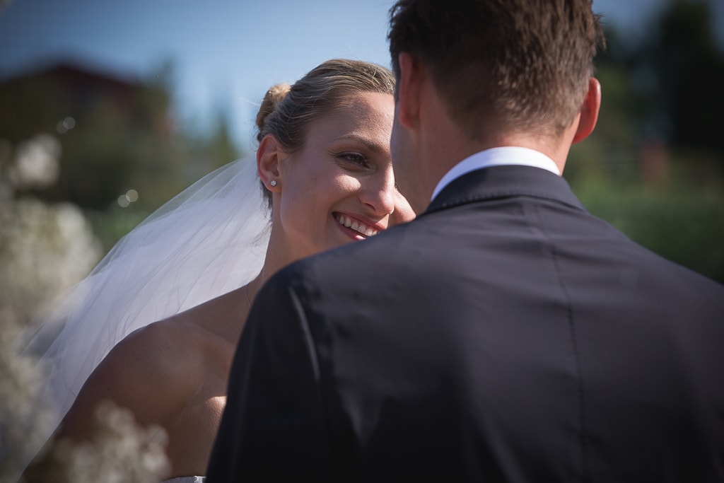 a bride smiles at the groom during an outdoor wedding ceremony in tuscany