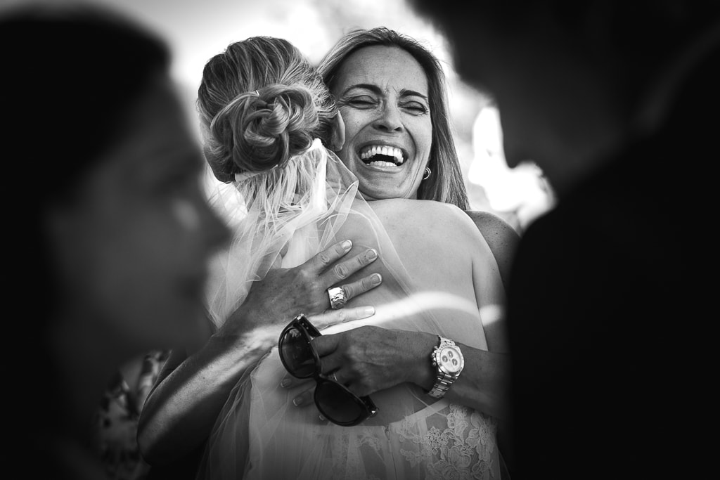 a stolen shot of the bride and a friend hugging at a wedding in tuscany