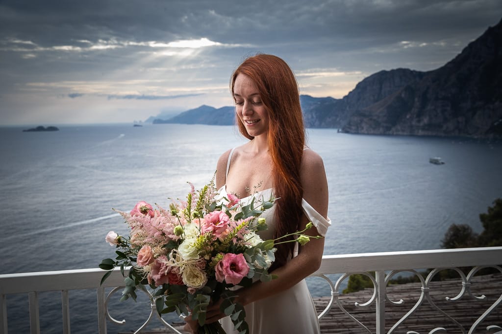portrait of a bride looking at her bouquet at hotel tritone in amalfi coast