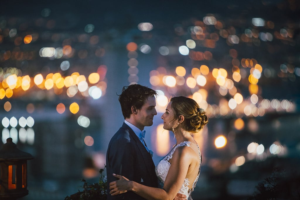 a wedding couple at dusk with blurred city lights in the background