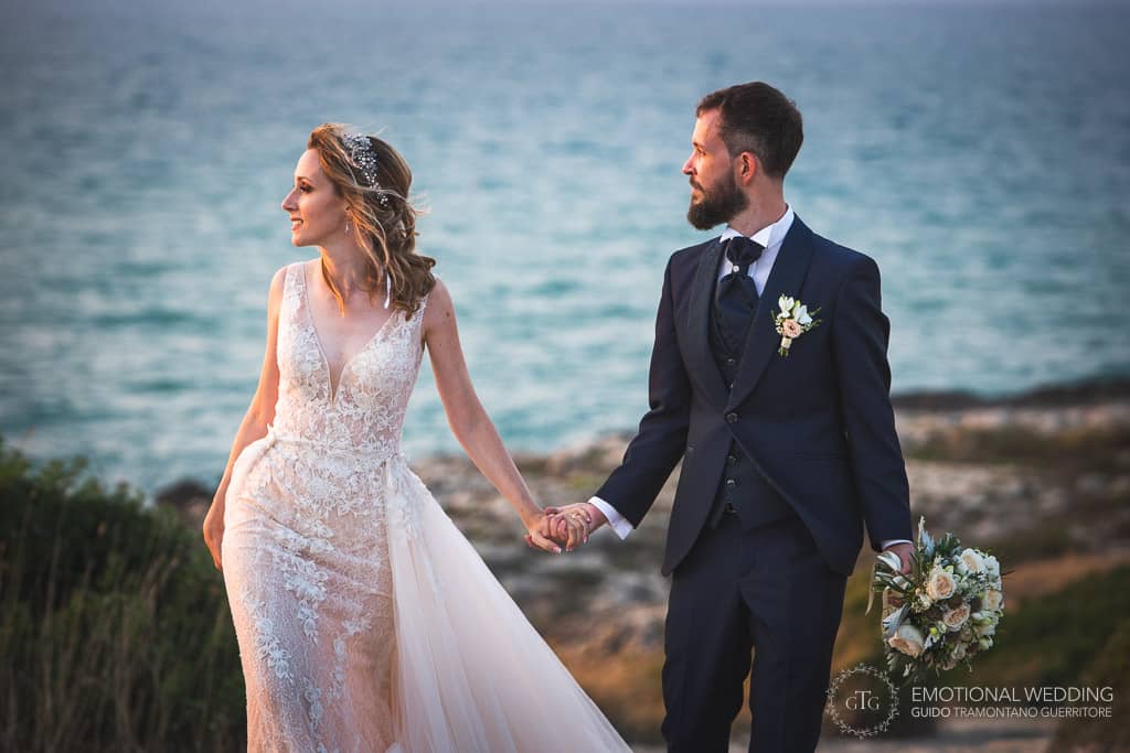 wedding couple walking at sunset by the sea in puglia