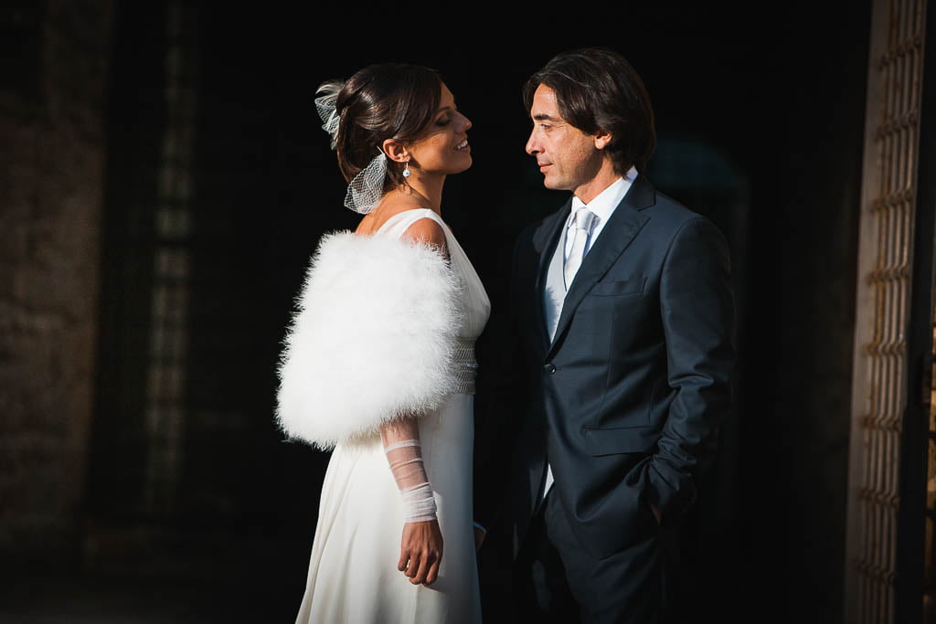 a wedding couple in front of each other lit by the sun on a dark background