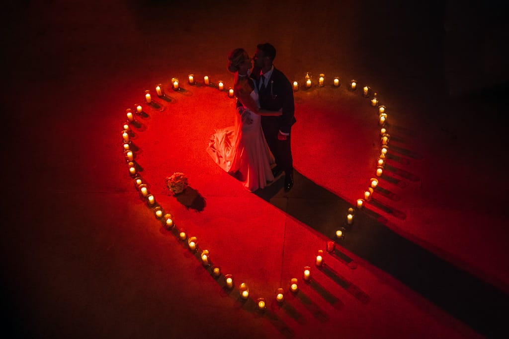 a wedding couple dancing inside a heart shaped area outlined with candles