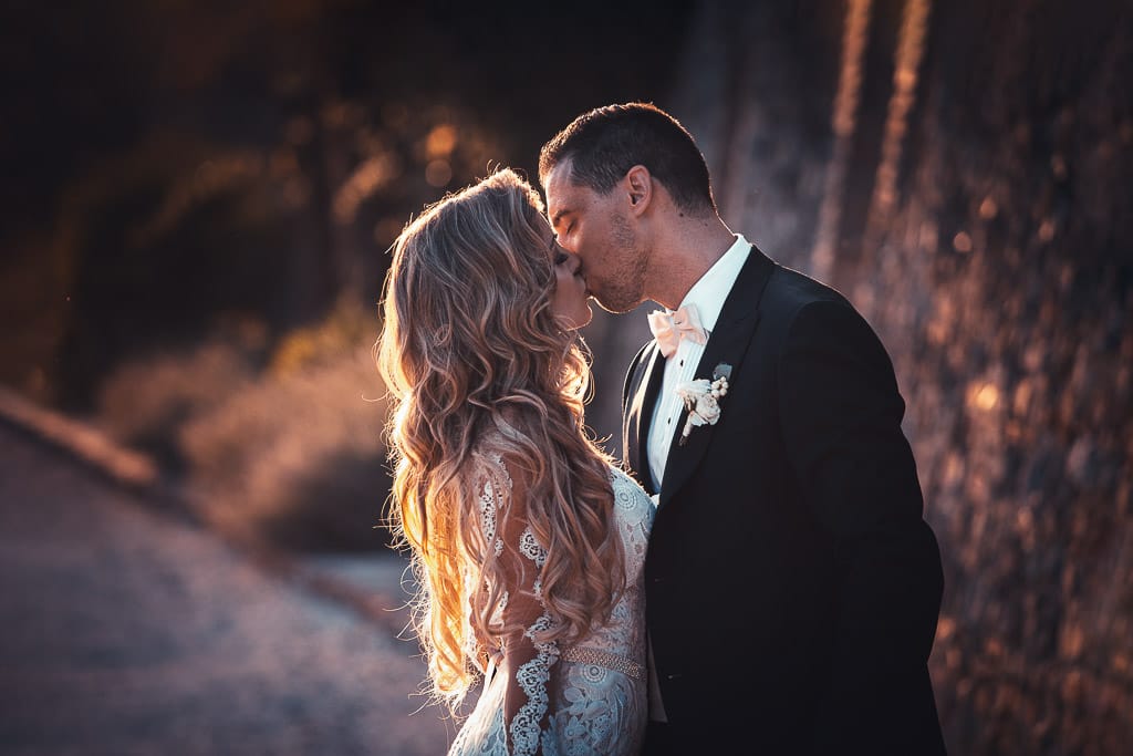 romantic kiss of a wedding couple in golden light