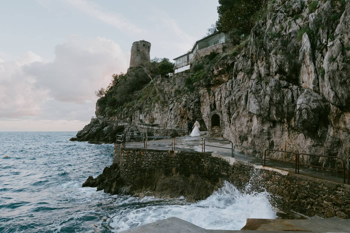 Romantic wedding couple walking a scenic path by the sea in Praiano — Amalfi Coast wedding photographer.