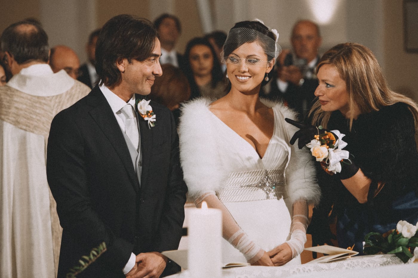 Film-inspired color edit of a candid ceremony moment where a bridesmaid leans in to speak to the groom, using Agfacolor tones with warm, nostalgic color rendering.