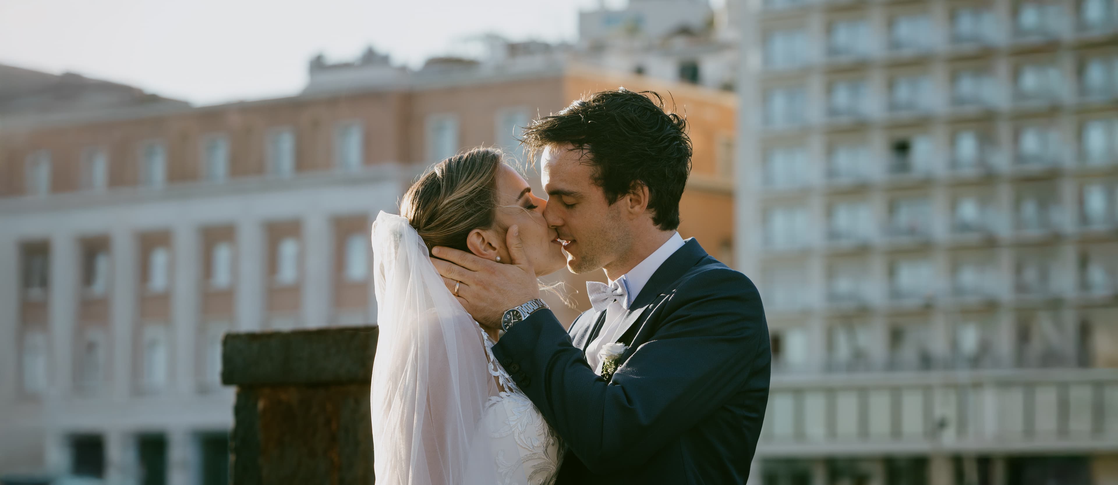 Couple embracing at sunset with Italian cityscape behind them — candid documentary style.