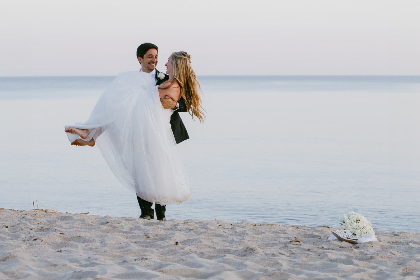 Groom joyfully lifting his bride during an intimate beach ceremony in Italy — Elopement wedding photographer in Italy.