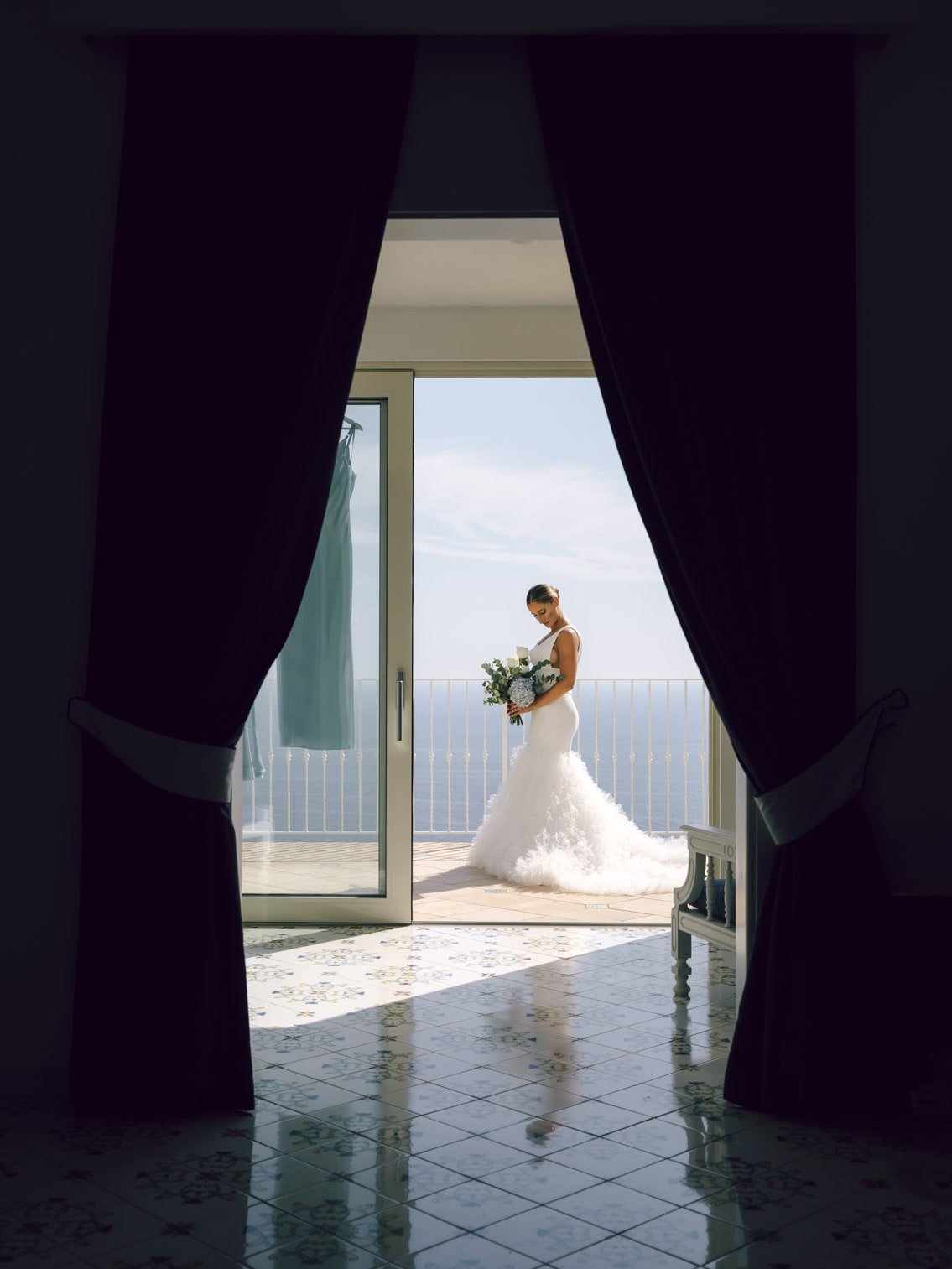 Bride on a sunlit hotel terrace in Praiano overlooking the Amalfi Coast.